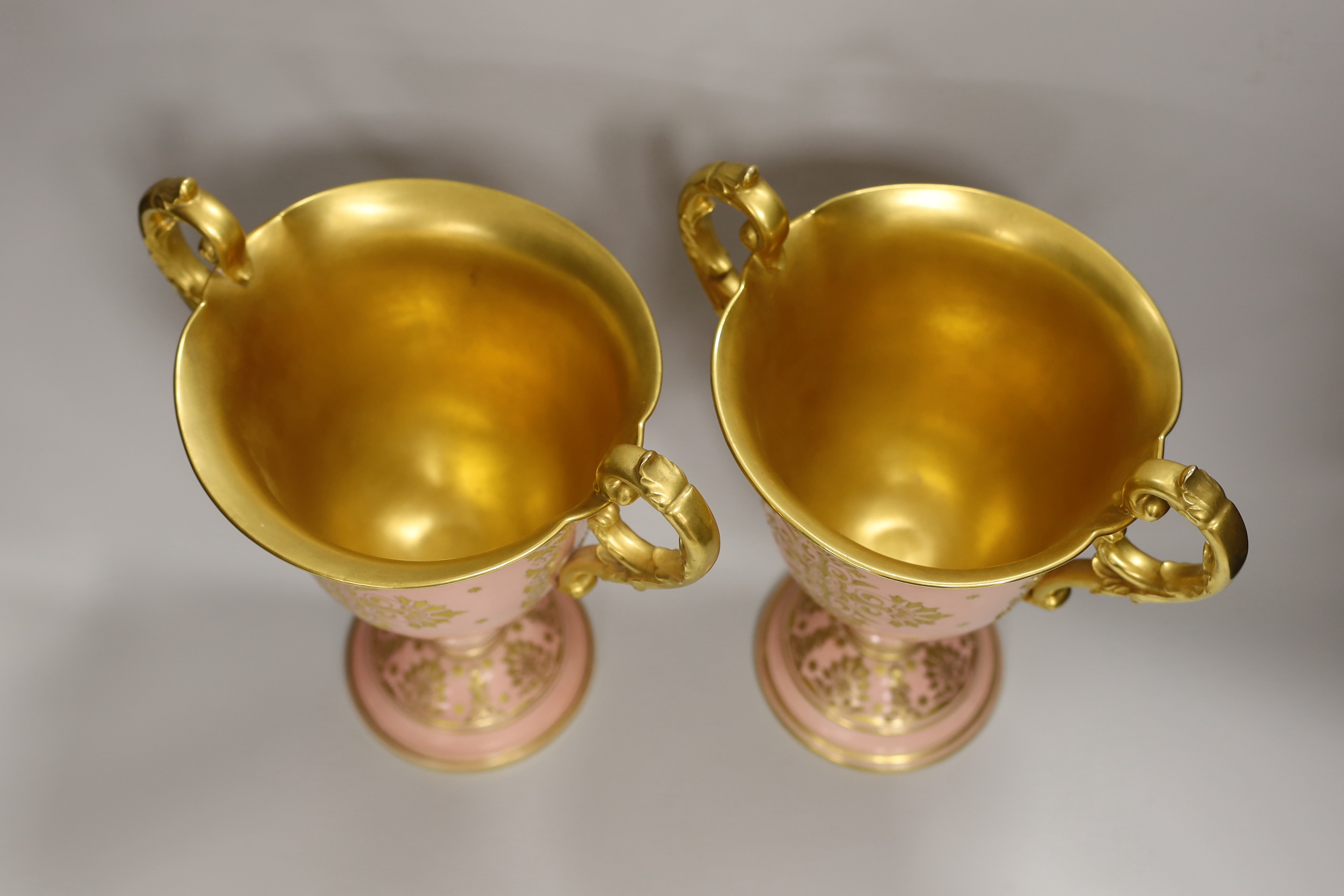 A pair of large Coalport salmon pink ground two handled loving cups, 28.5cm